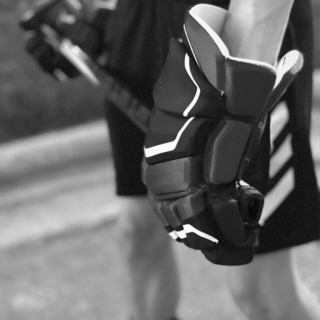Teenager holding stick wearing hockey gloves.