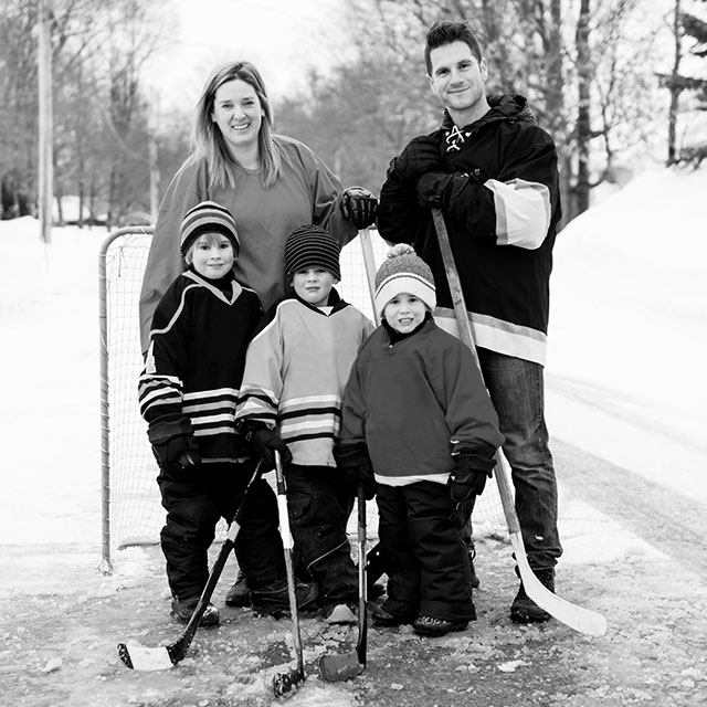 Family playing street hockey posing for a picture in front of the net